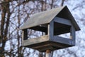 Wooden bird feeder in the Park, made in the form of a house, in the background autumn forest and trees. feeding birds in winter Royalty Free Stock Photo