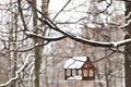 Wooden birdhouse for feeding birds under the snow on a tree branch. Winter time Royalty Free Stock Photo