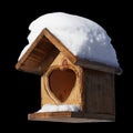 A wooden birdhouse with a heart-shaped entrance with snow on the roof isolated on a black background Royalty Free Stock Photo