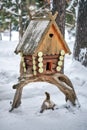 Wooden birdhouse. Log cabin birdhouse mounted on snag tree in snowy forest