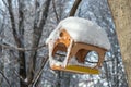 Wooden birdhouse in winter forest. Empty bird feeder close-up covered with snow.