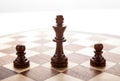 Wooden black chess king between black pawns Royalty Free Stock Photo