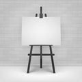 Wooden Black Easel with Mock Up Empty Blank Horizontal Canvas Standing on Floor in front of Brick Wall