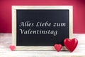 Wooden blackboard with red hearts and written sentence in German Alles Liebe zum Valentinstag, which means happy valentine