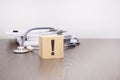 wooden block with black exclamation point, stethoscope on gray table. medical and education concept.