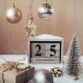 Wooden block calendar with 25 december date, Christmas decorations and gift box on beige background