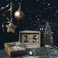 Wooden block calendar with 25 december date, Christmas decorations and gift box on black background with sparkles