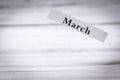 Wooden block displaying the word March against a light-colored wooden background, symbolizing the arrival of spring and Royalty Free Stock Photo