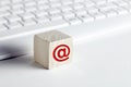 Wooden block with email symbol with computer keyboard background on white. Customer care, support or e-mail connection concept