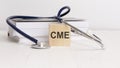 wooden block form the text CME - Continuing Medical Education - with stethoscope, notepad. medical concept Royalty Free Stock Photo