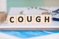 Wooden block form the word COUGH with stethoscope on the doctor`s desktop. Medical concept Royalty Free Stock Photo