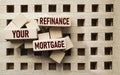 Wooden block forms the words REFINANCING YOUR MORTGAGE on a beautiful background, copy space