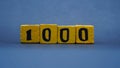 Wooden block with number 1000. Yellow color on dark background