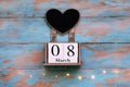 Wooden block save the date calendar, March 8, with heart shaped chalk board on vintage blue background with garland