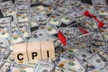 Wooden block with the word cpi and an empty shopping cart on a banknotes of dollar background. Business and CPI, consumer price