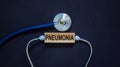 Wooden block with word `pneumonia` and stethoscope on black background. Medical concept