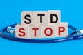 Wooden block with words Stop STD - Sexually transmitted diseases - with stethoscope on the table, insurance and medical concept,