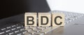 Wooden blocks with BDC text of concept on the laptop