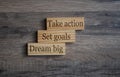 Wooden blocks with business terms Dream Big, set goals and take action on wooden background