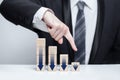 Wooden blocks with dark blue arrows icons, businessman in suit pointing down against white background, business decline loss drop