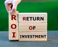 Wooden blocks form the expression `return of investment` ROI.