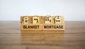 Wooden blocks form the words `blanket mortgage`, miniature house, wooden table. Beautiful white background, copy space. Business