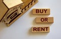 Wooden blocks form the words `buy or rent` near miniature house Royalty Free Stock Photo