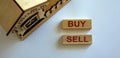 Wooden blocks form the words `buy sell` near miniature house Royalty Free Stock Photo