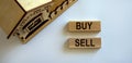 Wooden blocks form the words `buy sell` near miniature house. Beautiful white background. Business concept Royalty Free Stock Photo