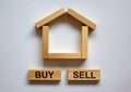 Wooden blocks form the words `buy sell` near miniature house. Beautiful white background, copy space. Business concept Royalty Free Stock Photo