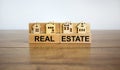 Wooden blocks form the words `real estate`, miniature house, wooden table. Beautiful white background, copy space. Business Royalty Free Stock Photo