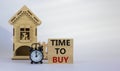 Wooden blocks form the words `time to buy` near miniature house. Black alarm clock. Beautiful white background. Business concept Royalty Free Stock Photo