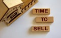 Wooden blocks form the words `time to sell` near miniature house. Beautiful white background, copy space. Business concept Royalty Free Stock Photo