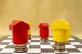 Wooden blocks houses on coin stacks used as chess pieces, soft focus cose up