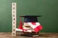 Wooden blocks with letters, diploma, books, academic cap and canadian flag on wooden surface