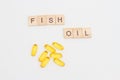 Wooden blocks with letters and words FISH OIL and capsules with fish oil and omega 3 on white background Royalty Free Stock Photo