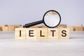 Wooden blocks with a magnifying glass text: IELTS. International English Language Testing System