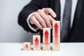 Wooden blocks with red arrows icons, businessman in black suit holding block against white background, business profit success Royalty Free Stock Photo