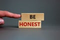 Wooden blocks with the text `be honest` on beautiful grey background. Male hand. Business concept, copy space