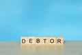Wooden blocks with text DEBTOR. Financial concept Royalty Free Stock Photo