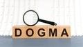 Wooden blocks with the text: dogma with magnifying glass Royalty Free Stock Photo