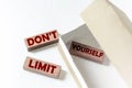 Wooden blocks with text DON`T LIMIT YOURSELF in a box on a white background