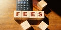 Wooden Blocks with the text: Fees and calculator on wooden table. Taxes and fees business financial concept Royalty Free Stock Photo