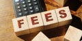 Wooden Blocks with the text: Fees and calculator on wooden table. Taxes and fees business financial concept Royalty Free Stock Photo