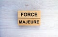 Wooden blocks with text Force Majeure on the wooden background