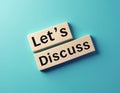 Wooden blocks with text Let Discuss on blue background. Concept for communication, business meeting, idea sharing, and Royalty Free Stock Photo