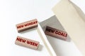 Wooden blocks with text New Monday New Week New Goals in a box on a white background