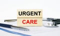 Wooden blocks with text Urgent Care on a clipboard, stethoscope and pen