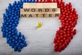 Wooden blocks in a white and grey board with the text words matter, surrounded by blue and red wooden figurines, yellow speaker