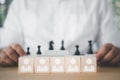 Wooden blocks with white human icons and businessman looking black chess. Leadership and teamwork concept Royalty Free Stock Photo